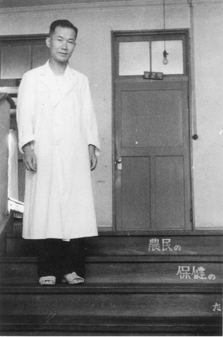 当時の院長室（２階）の前で。階段には「農民の保健のために」と書いてある。昭和２６年。